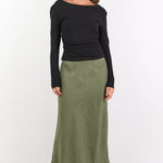 Woman wearing a black top and green skirt on a white background