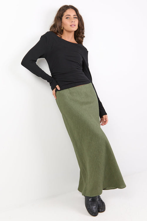 Woman wearing a black top and green skirt against a white background