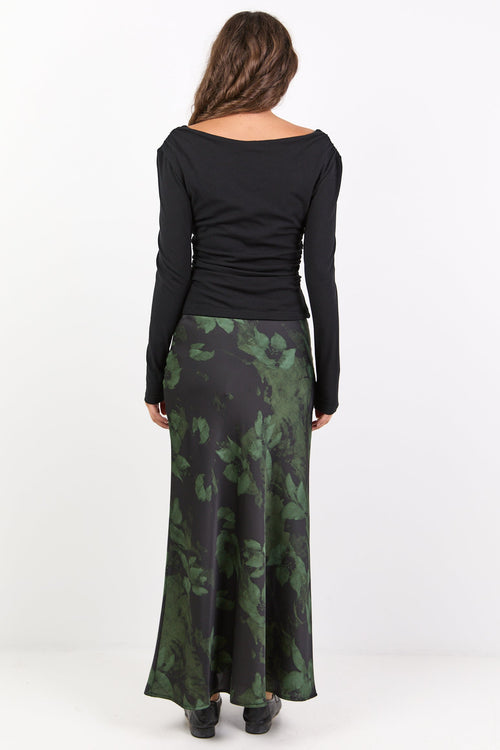 Woman wearing a black long-sleeve top and green camouflage skirt on a white background