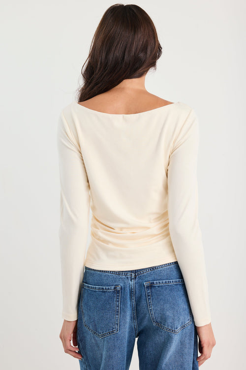 Woman wearing a ruched cream long sleeve top
