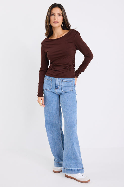 model wears a brown long sleeve top with light blue jeans 