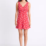 model wearing a red white polka dot mini dress with a V neck and button front