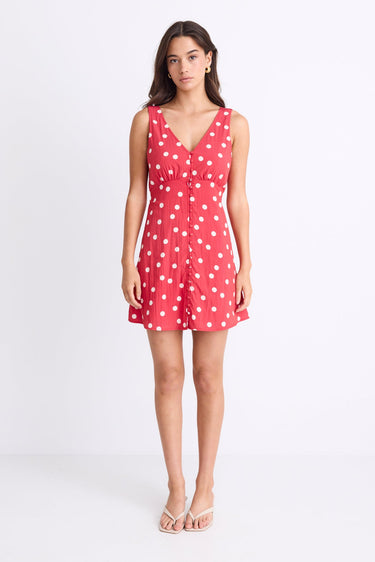 model wearing a red white polka dot mini dress with a V neck and button front