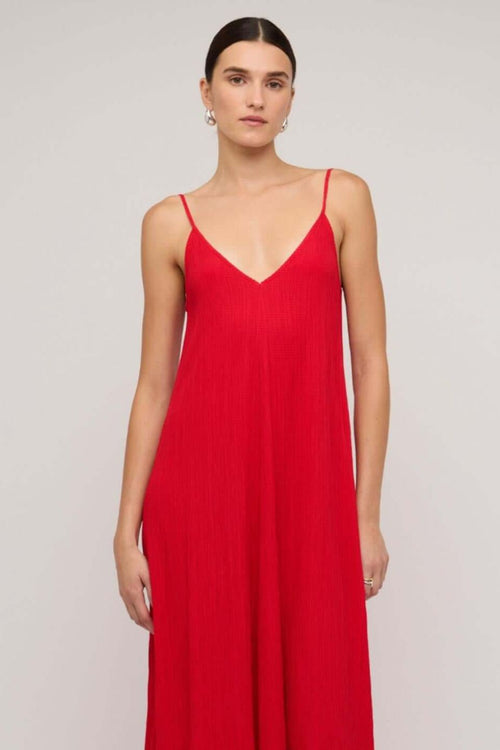 Bright red textured maxi dress with thin spaghetti straps and a deep V-neckline, styled in a relaxed fit, worn by a model against a neutral background.