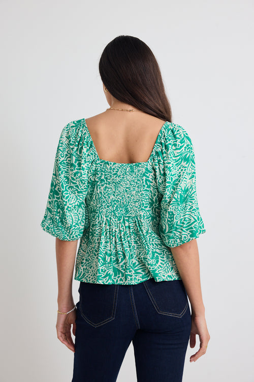 model wears green floral puff sleeve top and blue jeans