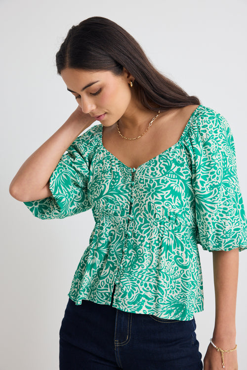 model wears green floral puff sleeve top and blue jeans