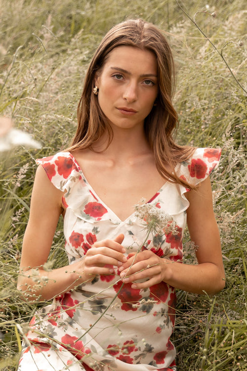 Woman in a floral dress sitting in a grassy field