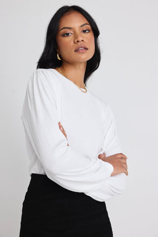 Models wears a white long sleeve top with black skirt 