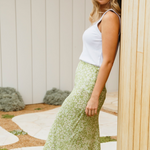 model wears green floral midi skirt and white tank top