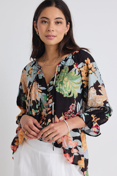 model wears a black tropical print blouse