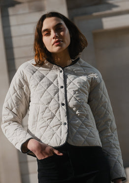 Woman wearing a quilted jacket standing in front of a classical building.