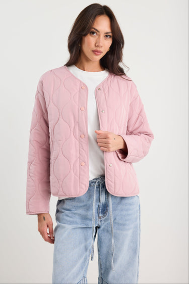 Woman wearing a pink quilted jacket and blue jeans