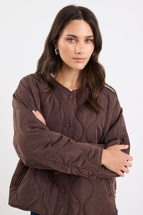 Woman wearing a brown quilted jacket on a white background