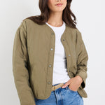 Woman wearing a green jacket and blue jeans against a white background