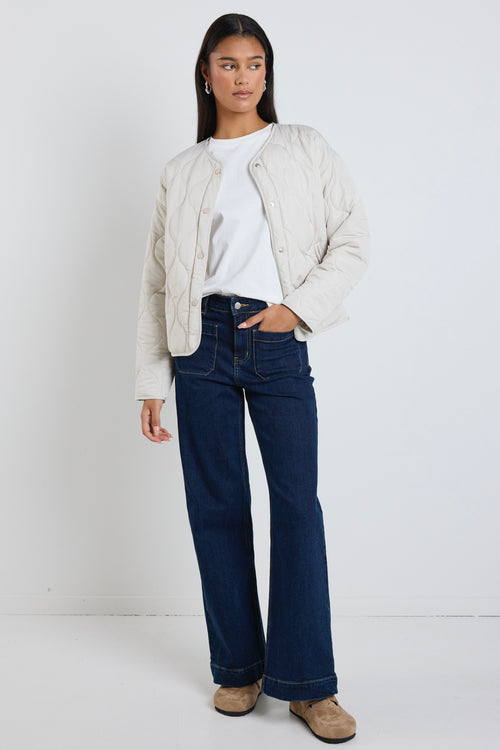  A quilted putty puffer jacket styled with a white tee and indigo denim, creating a relaxed yet elevated everyday look.