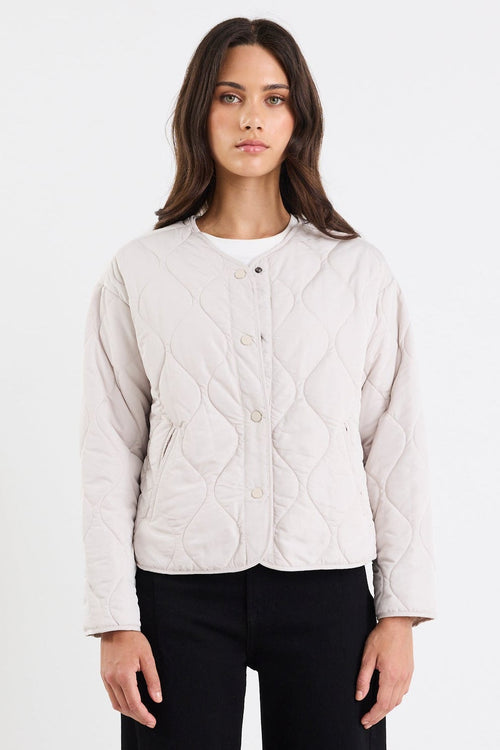 Person wearing a light gray quilted jacket, black pants, and white sneakers on a white background