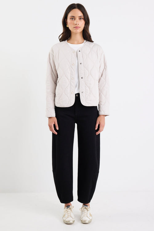 Person wearing a light-colored jacket and black pants on a white background