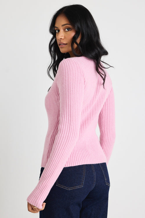 Model wears a pink long sleeve knit top