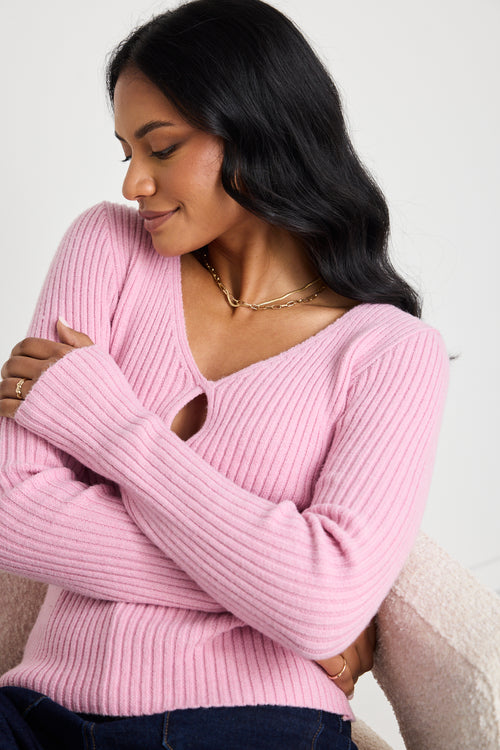 Model wears a pink long sleeve knit top