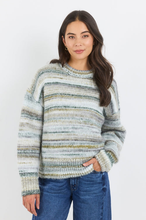 Woman wearing a striped sweater and blue jeans against a white background