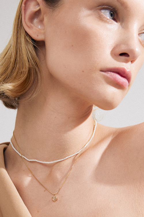 model wearing double chain necklace including pearl necklace and gold necklace with heart pendant