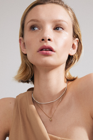 model wearing double chain necklace including pearl necklace and gold necklace with heart pendant