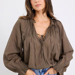 model wears a olive blouse with light blue jeans