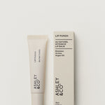 Lip balm and packaging with 'Ashley & Co' branding on a light gray background