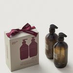 Two brown bottles with black caps and a matching box with a red bow on a white background.