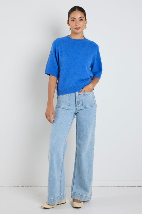 Model wears an azure blue knit tee with light blue jeans 
