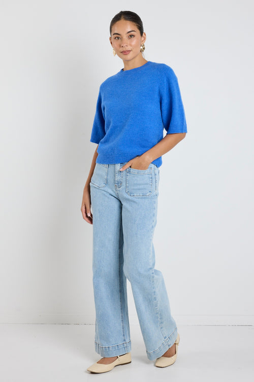 Model wears an azure blue knit tee with light blue jeans 