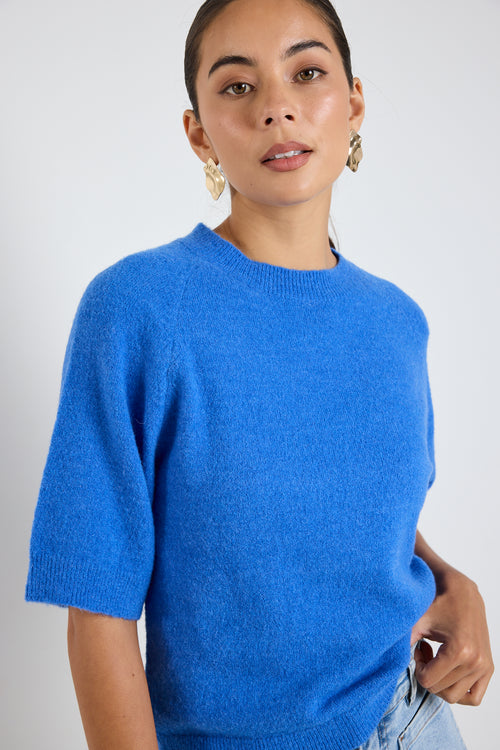 Model wears an azure blue knit tee with light blue jeans 