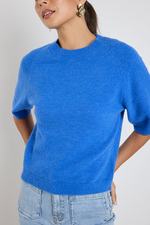 Model wears an azure blue knit tee with light blue jeans 