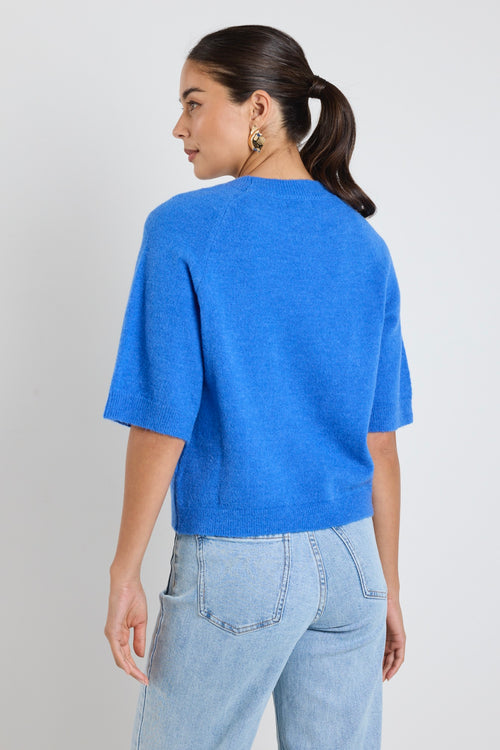 Model wears an azure blue knit tee with light blue jeans 