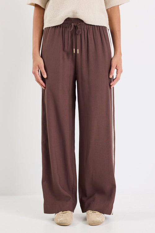 Person wearing brown wide-leg pants with a white background