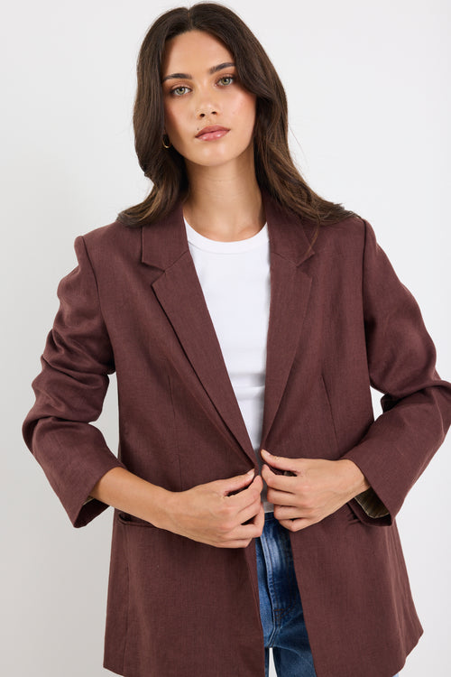 Woman wearing a brown blazer over a white shirt on a white background