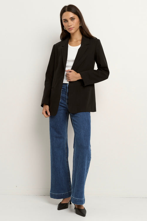 model wears a black blazer with blue jeans