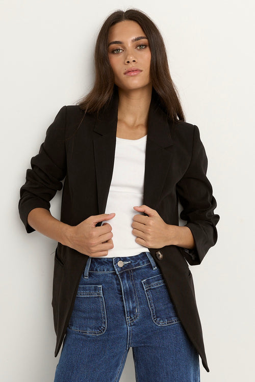 model wears a black blazer with blue jeans