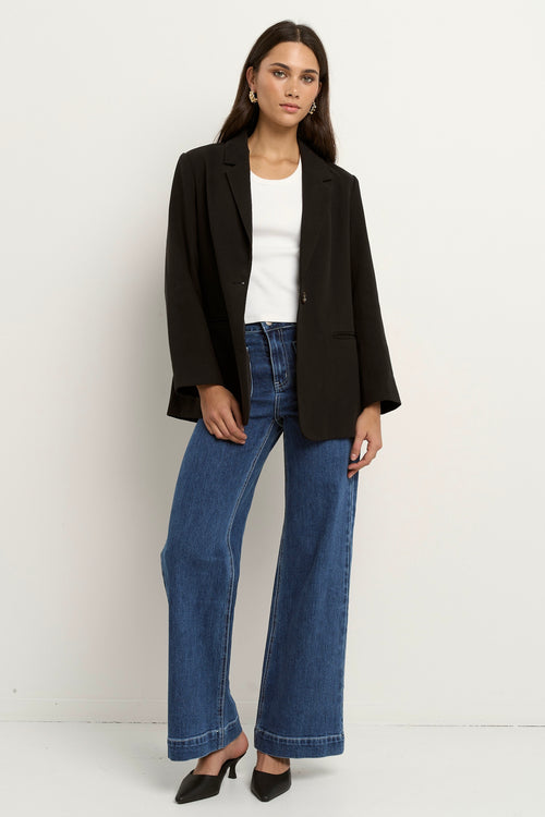 model wears a black blazer with blue jeans
