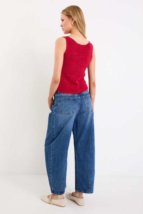 woman wearing a red knit top and blue jeans