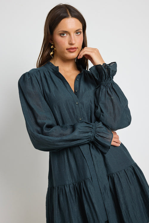 Model wears a long sleeve forest green mini dress with tie waist. 