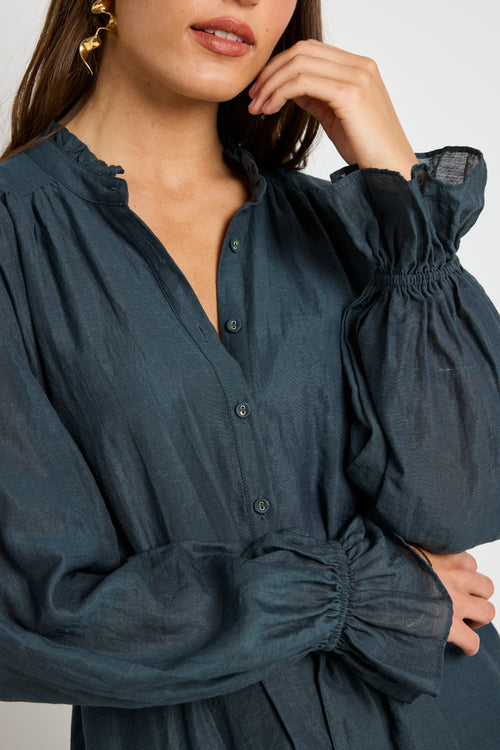 Model wears a long sleeve forest green mini dress with tie waist. 
