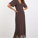 Woman wearing a brown dress with white polka dots on a white background