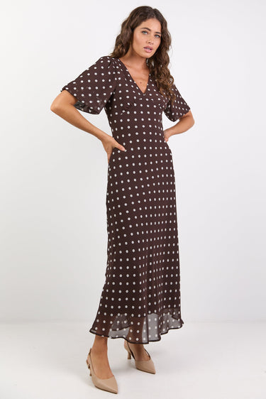 Woman wearing a brown dress with white polka dots on a white background