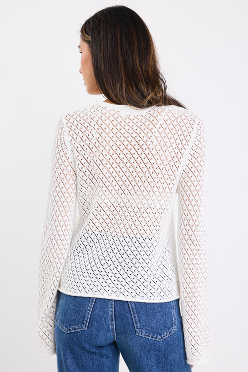 model wears a white lace knit top with mid blue jeans