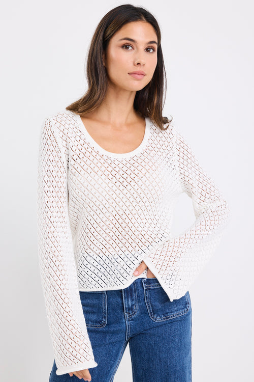model wears a white lace knit top with mid blue jeans