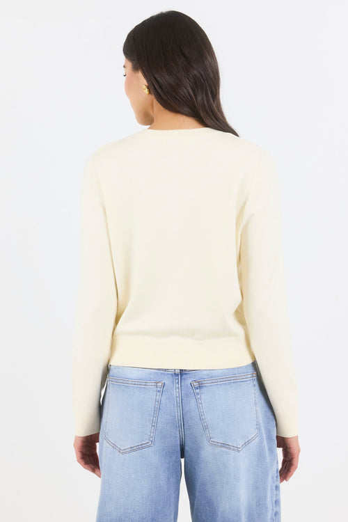 Person wearing a light-colored sweater and light blue jeans on a white background