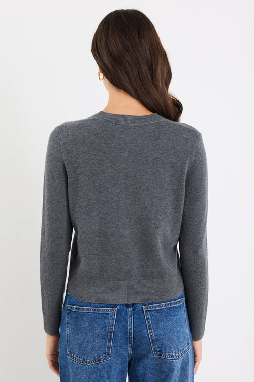 Person wearing a gray sweater and blue jeans on a white background