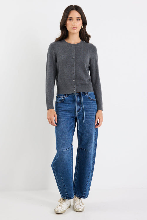 Woman wearing a gray cardigan and blue jeans on a white background