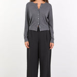 Woman wearing a gray cardigan and black pants on a white background